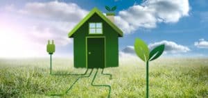 Casa verde collegata a una spina elettrica su un prato