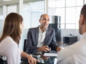 Un consulente per mutui discute i dettagli di un piano di mutuo con due clienti in un ufficio.