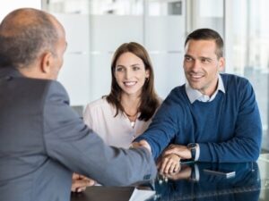 Un consulente per mutui stringe la mano a una coppia dopo aver finalizzato un accordo di mutuo.